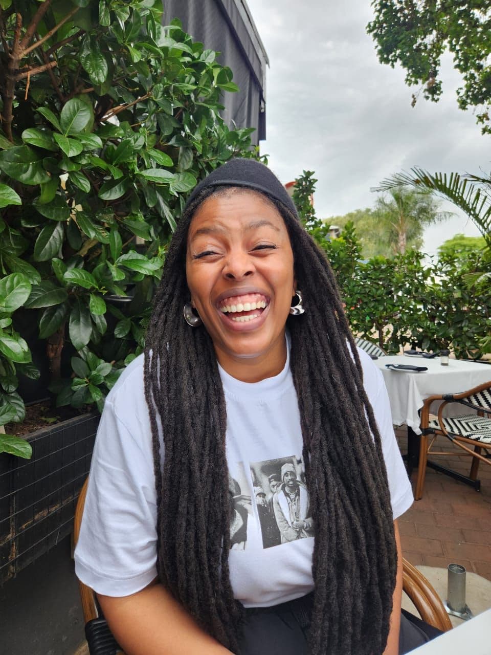 A photograph of a woman laughing at a garden table