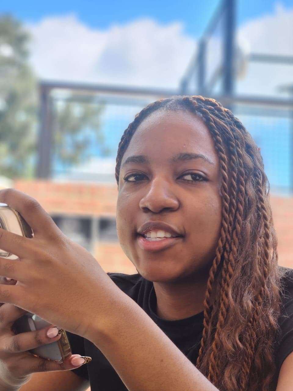 A photograph of a young woman with braids holding her phone