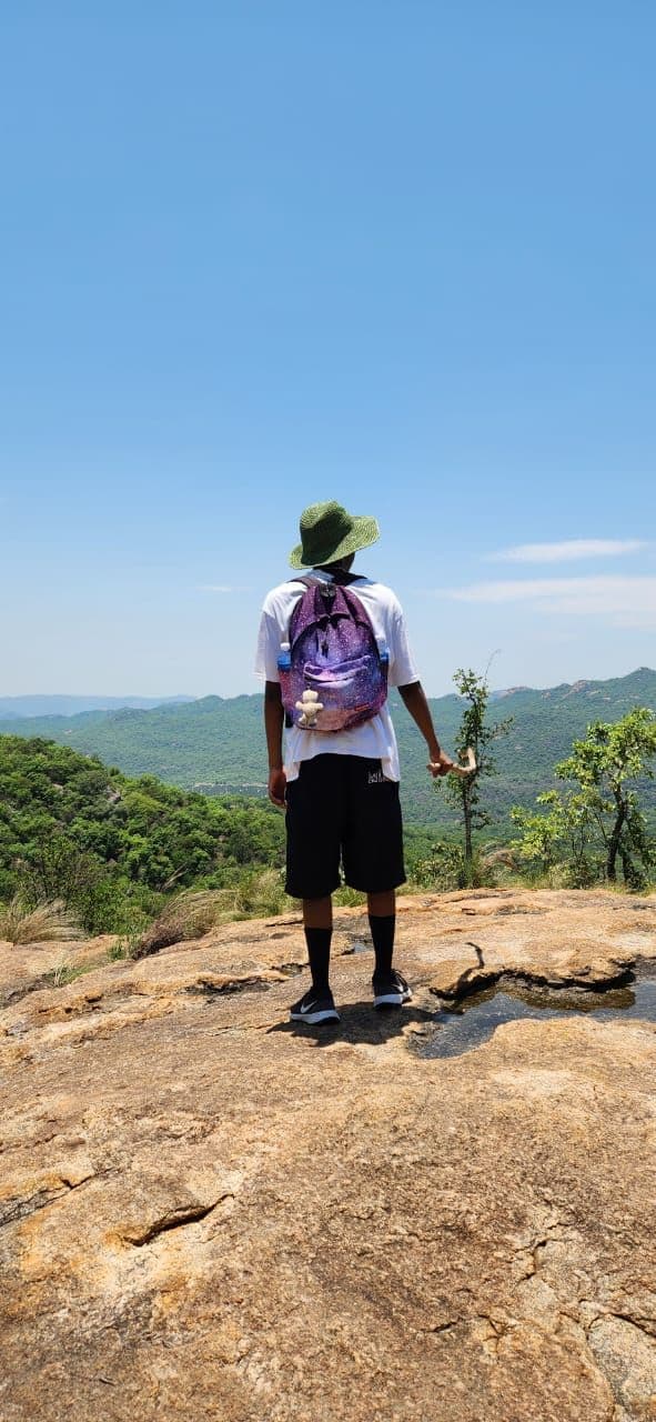A photograph of a hiker looking out over green hills